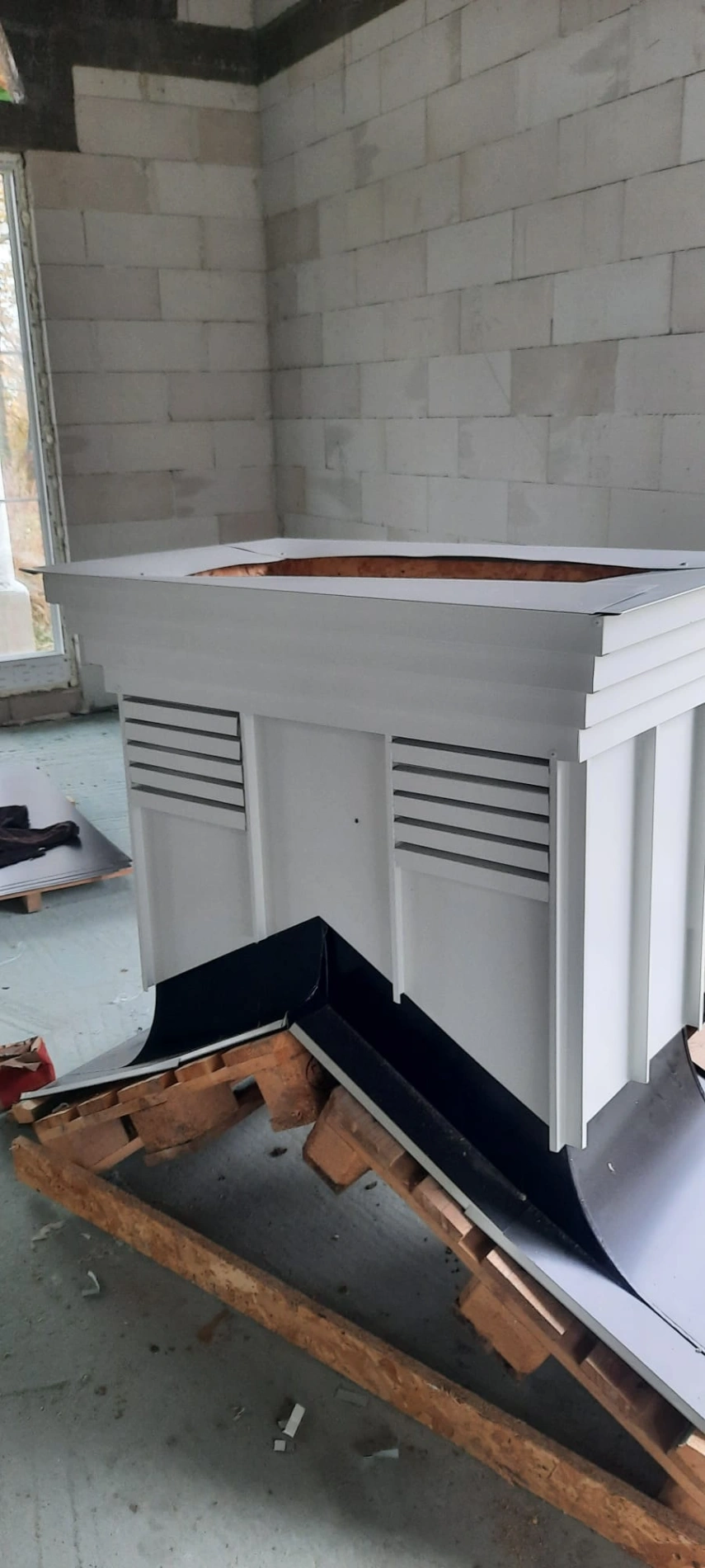 Obróbka komina z blachy w surowej konstrukcji dachu